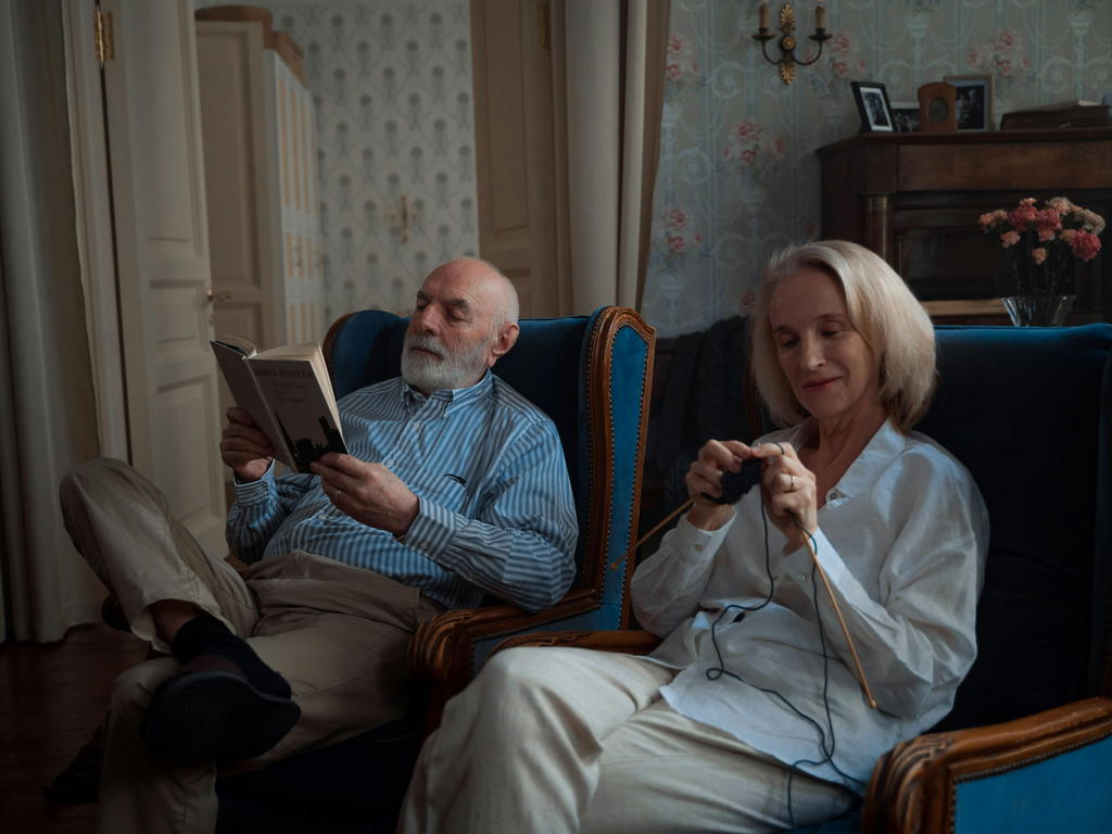 Senior Man Sitting Comfortably In An Armchair Reading A Book With A Smile — senior care guide